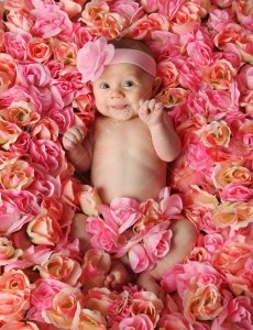 8046097-adorable-petite-fille-souriant-située-dans-un-lit-de-roses-roses-.jpg