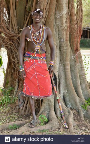 guerrier-massai-portant-des-vetements-traditionnels-et-debout-dans-une-pose-typique-sur-une-ja...jpg